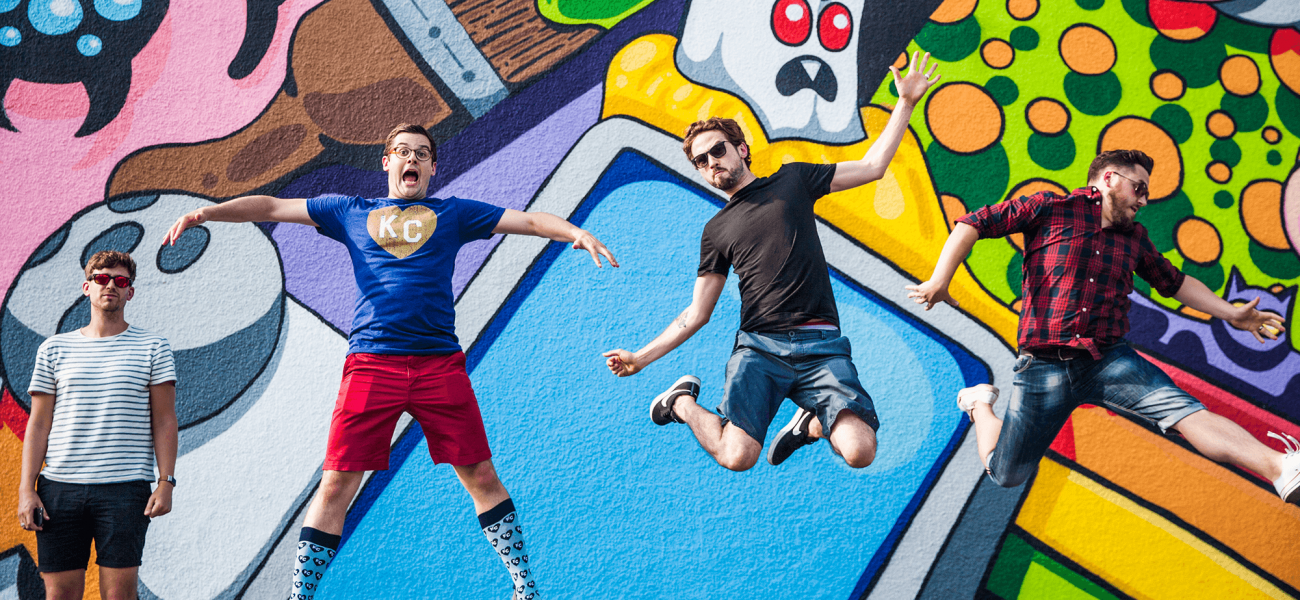 Image of young men posing dancing in front of graffiti wall