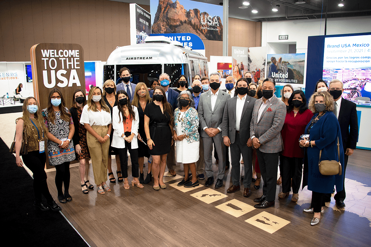Group of people at IPW 2021 event with USA travel displays.
