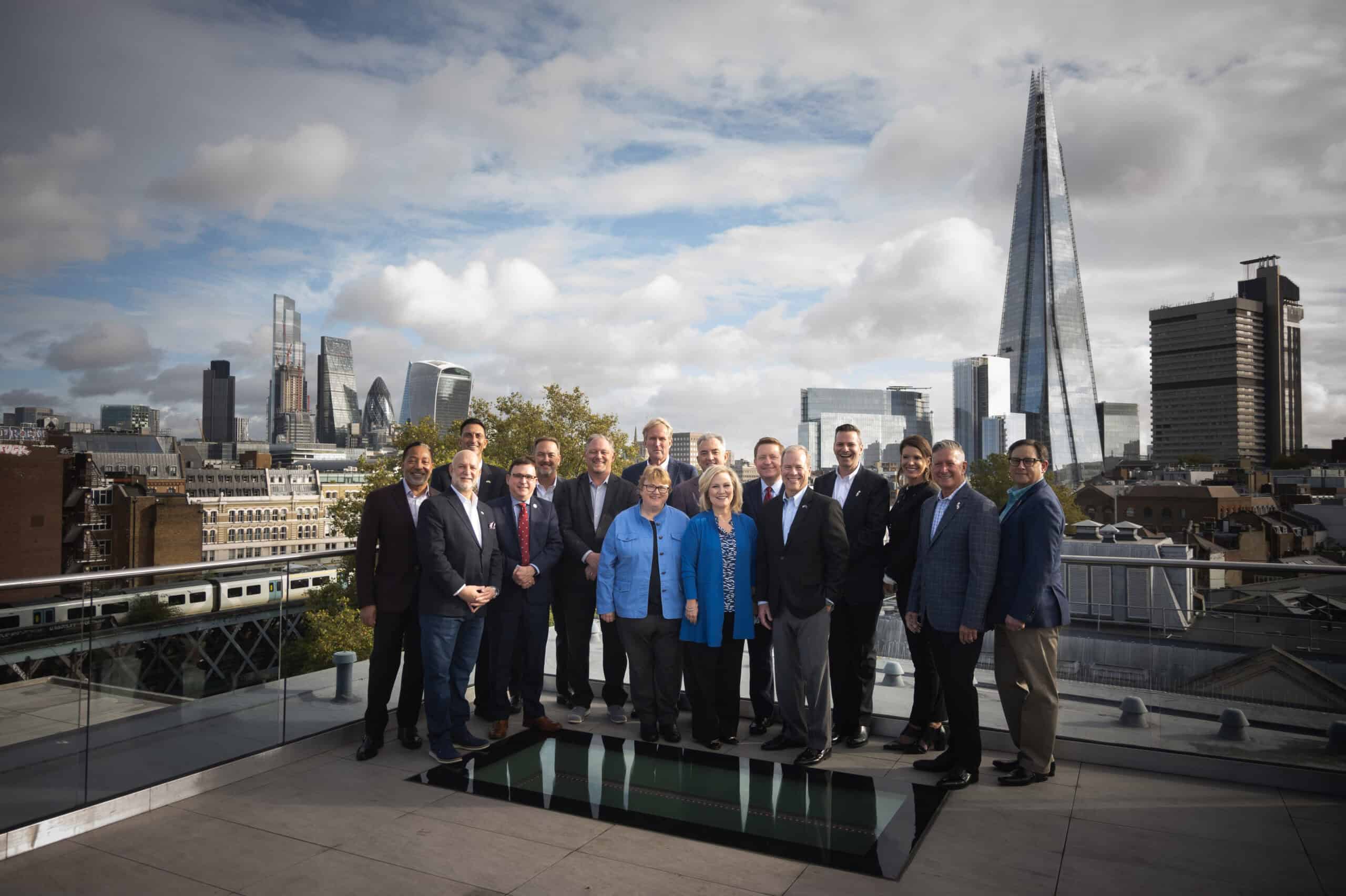 Business professionals on rooftop with London skyline and The Shard in background.