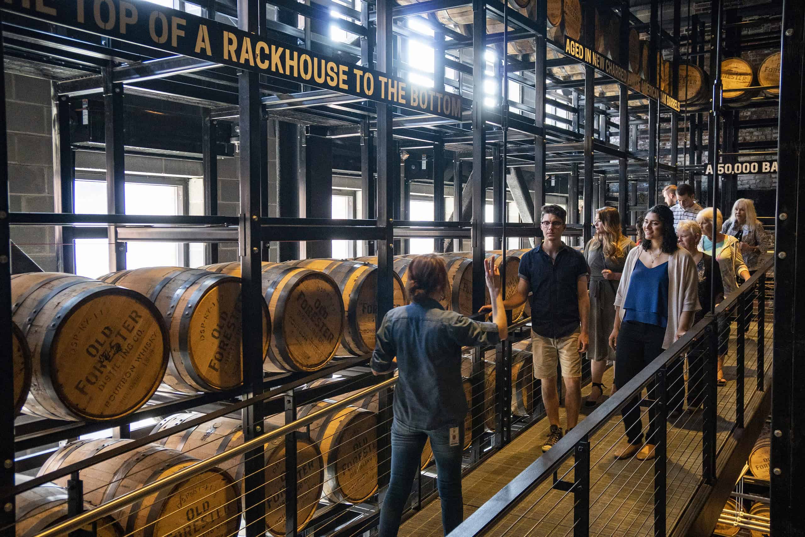 Visitors explore bourbon barrels at a Kentucky distillery rackhouse.
