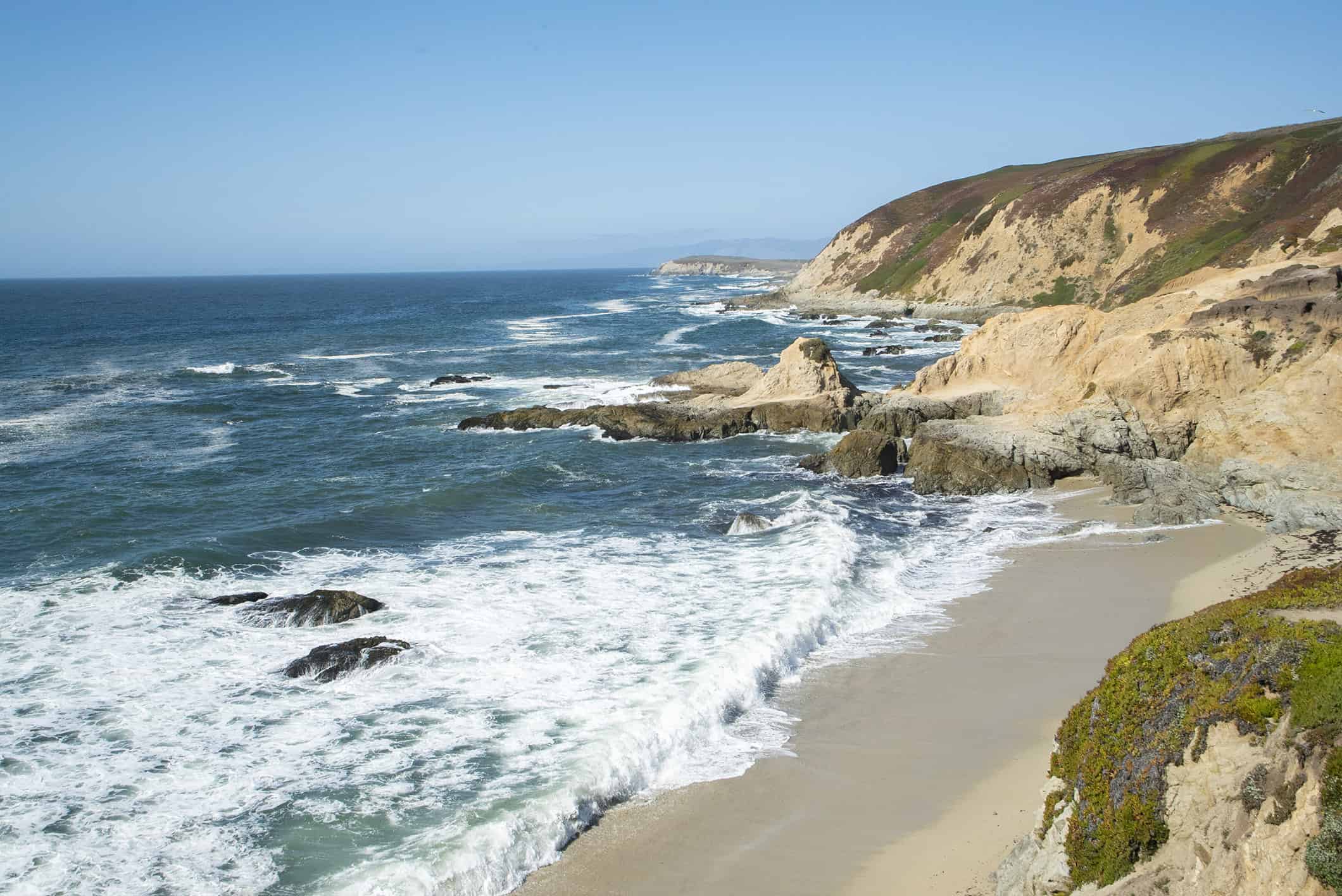 Beautiful California coastline with cliffs, sandy beach, and ocean waves.
