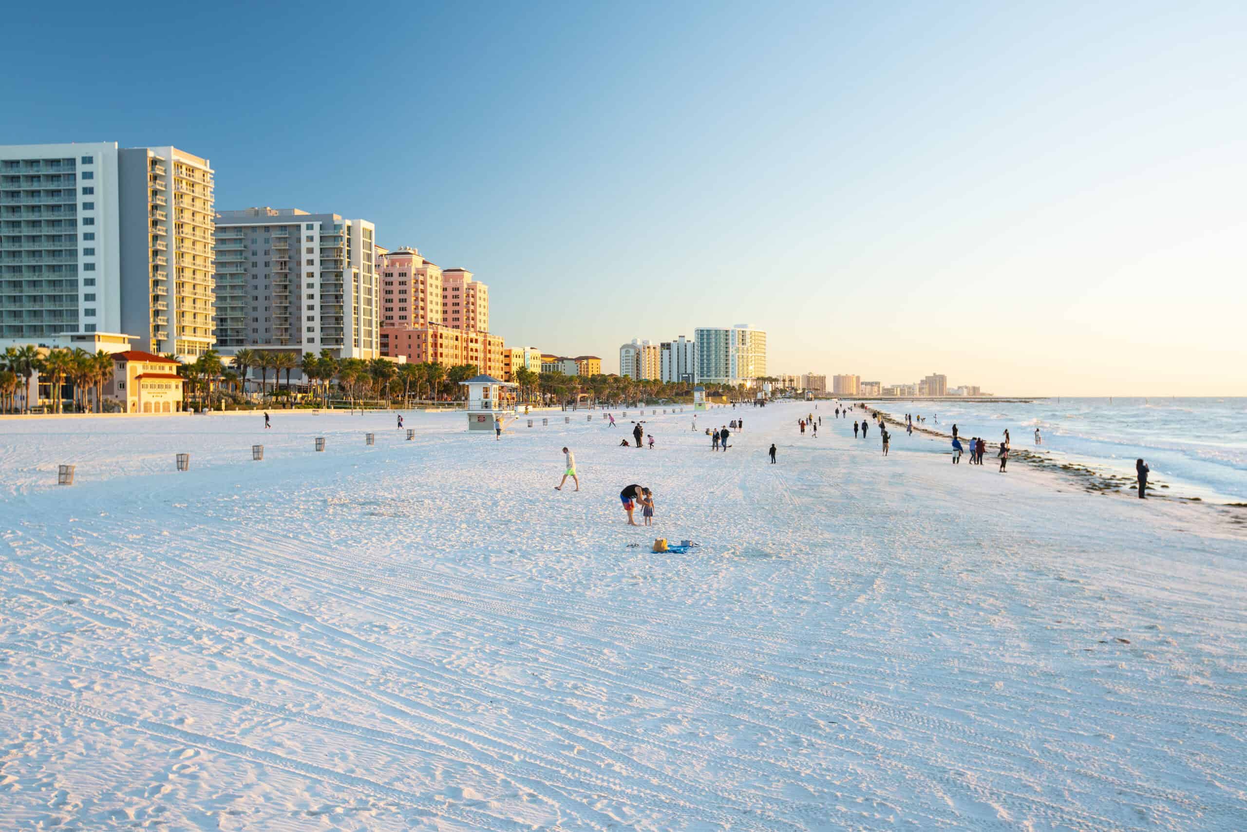 Miami Beach with high-rise hotels and people enjoying the beach at sunset.