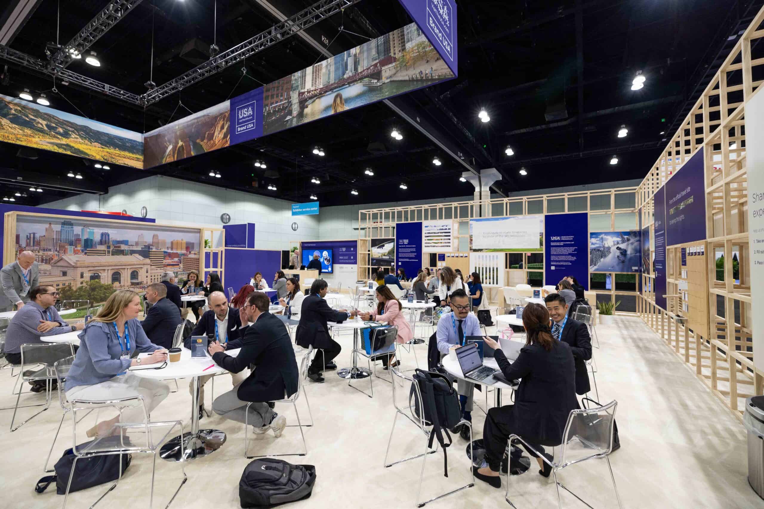 Business professionals networking at the Brand USA booth during IPW 2024.