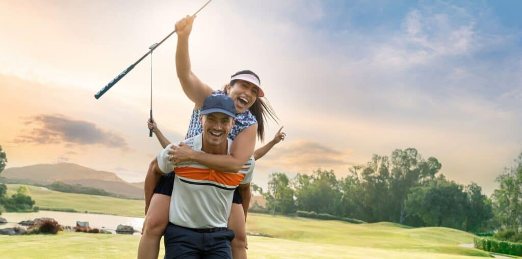 Smiling man and girl playing golf outdoors at sunset.