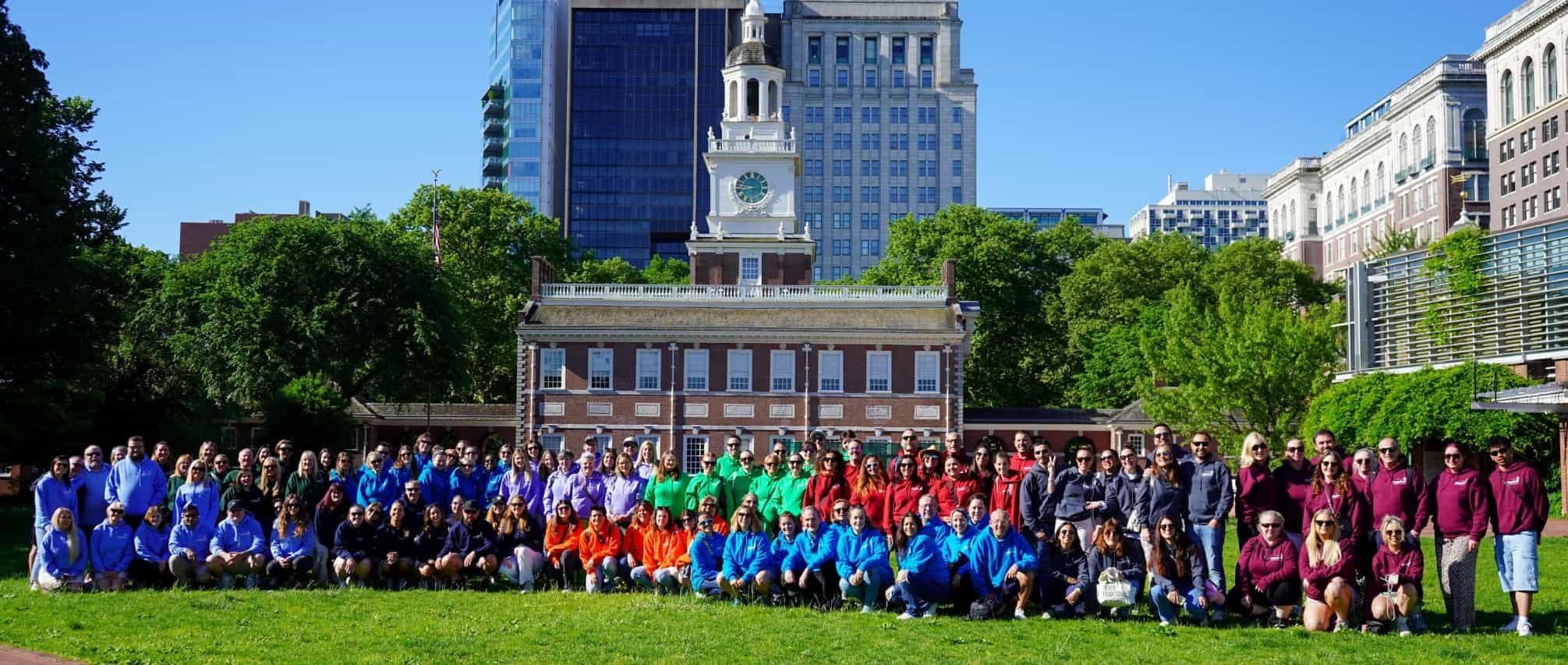 Group photo of diverse participants at The Brand USA event in a city park.