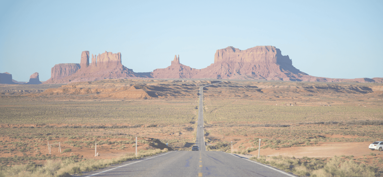Long straight road leading to iconic Monument Valley mesas in Arizona.