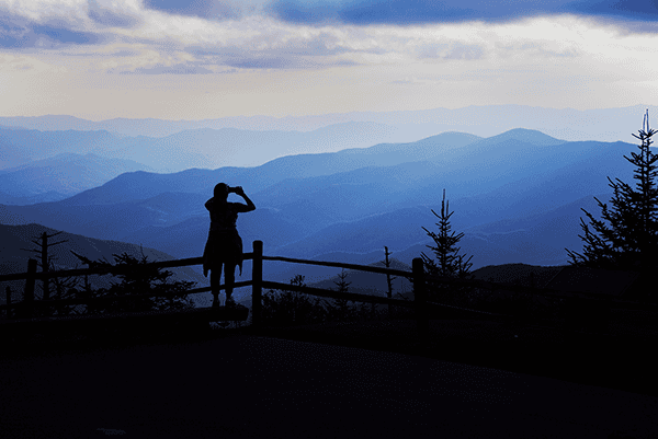 Person taking photos of mountain landscape at sunset.