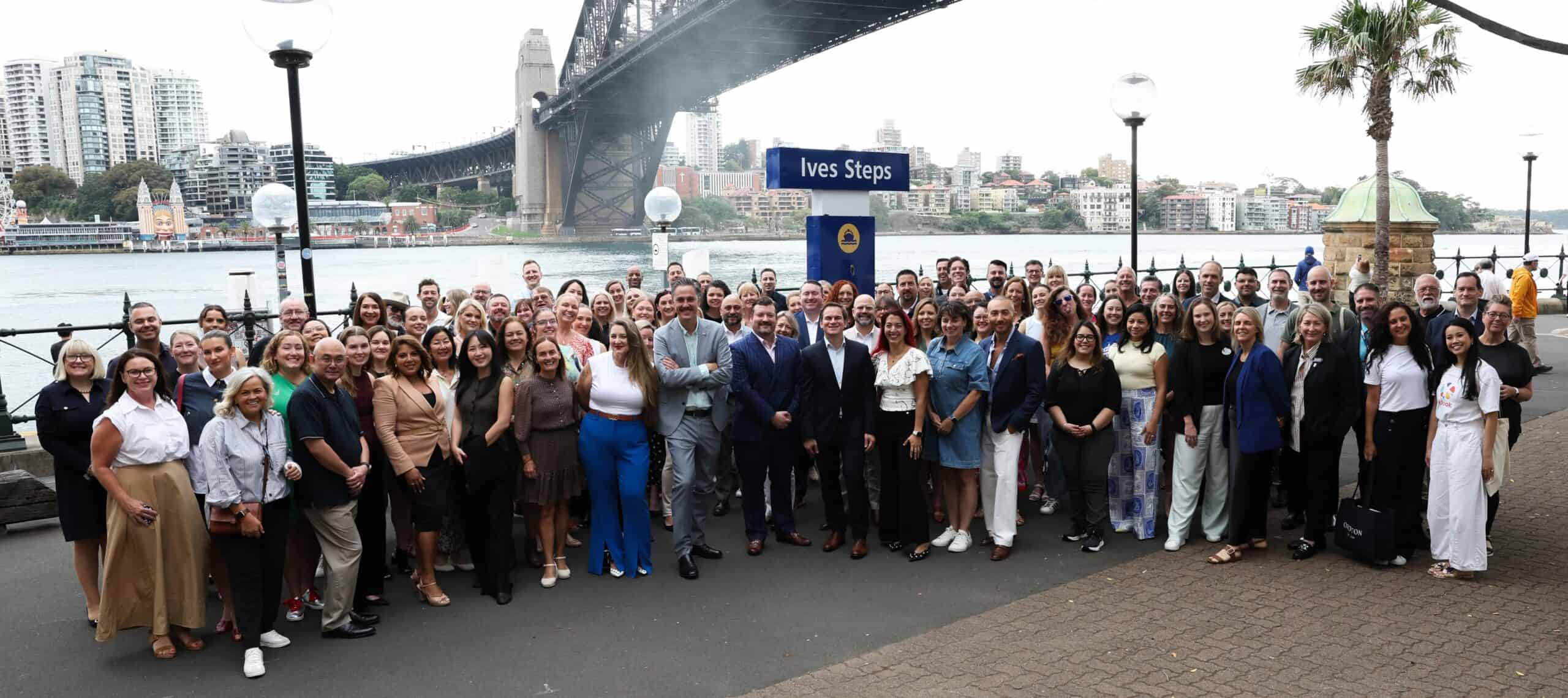 Trade and media professionals gather by Sydney Harbour for a group photo.
